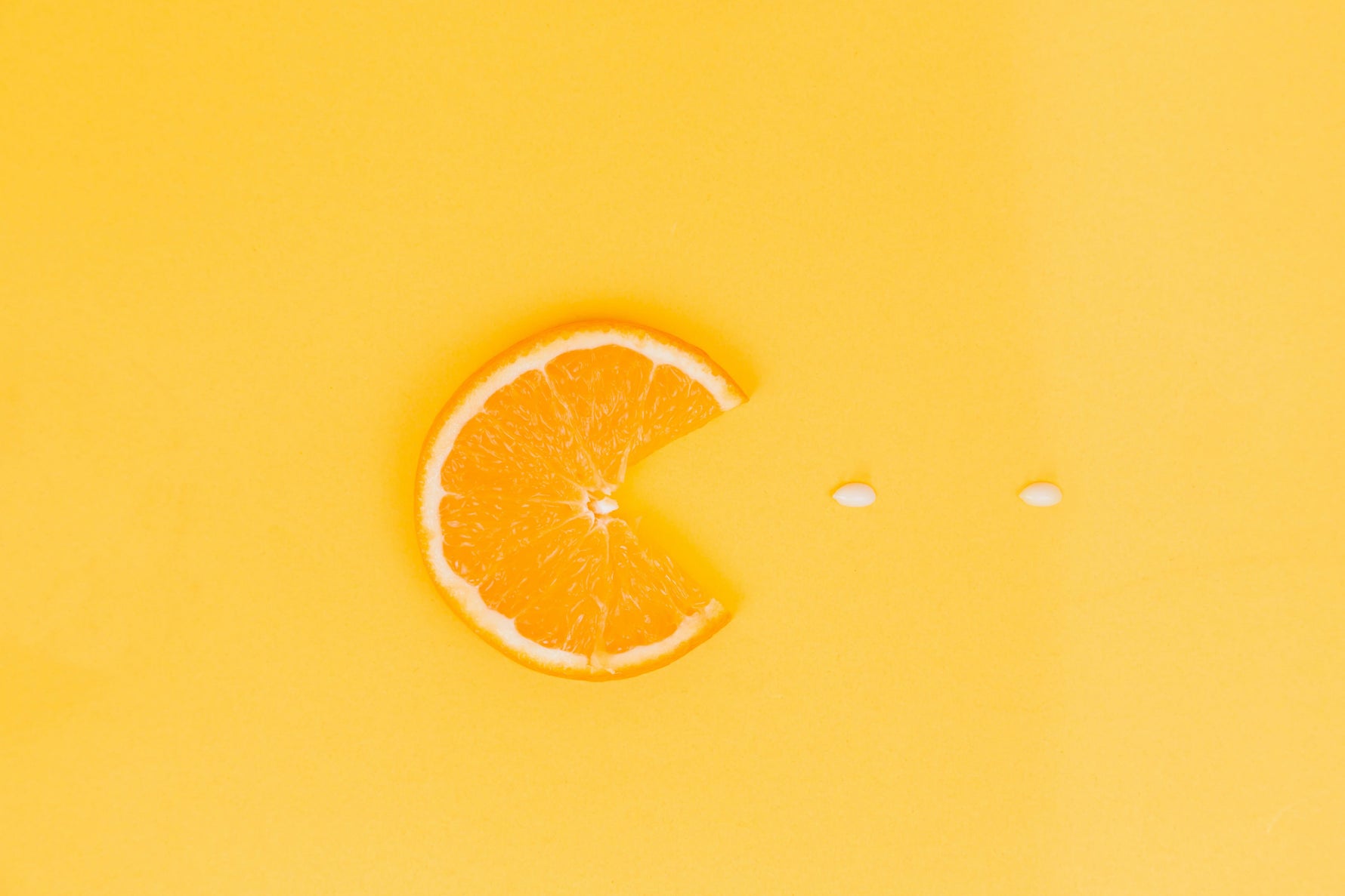 Orange slice with a bite taken out of it on a bright yellow background