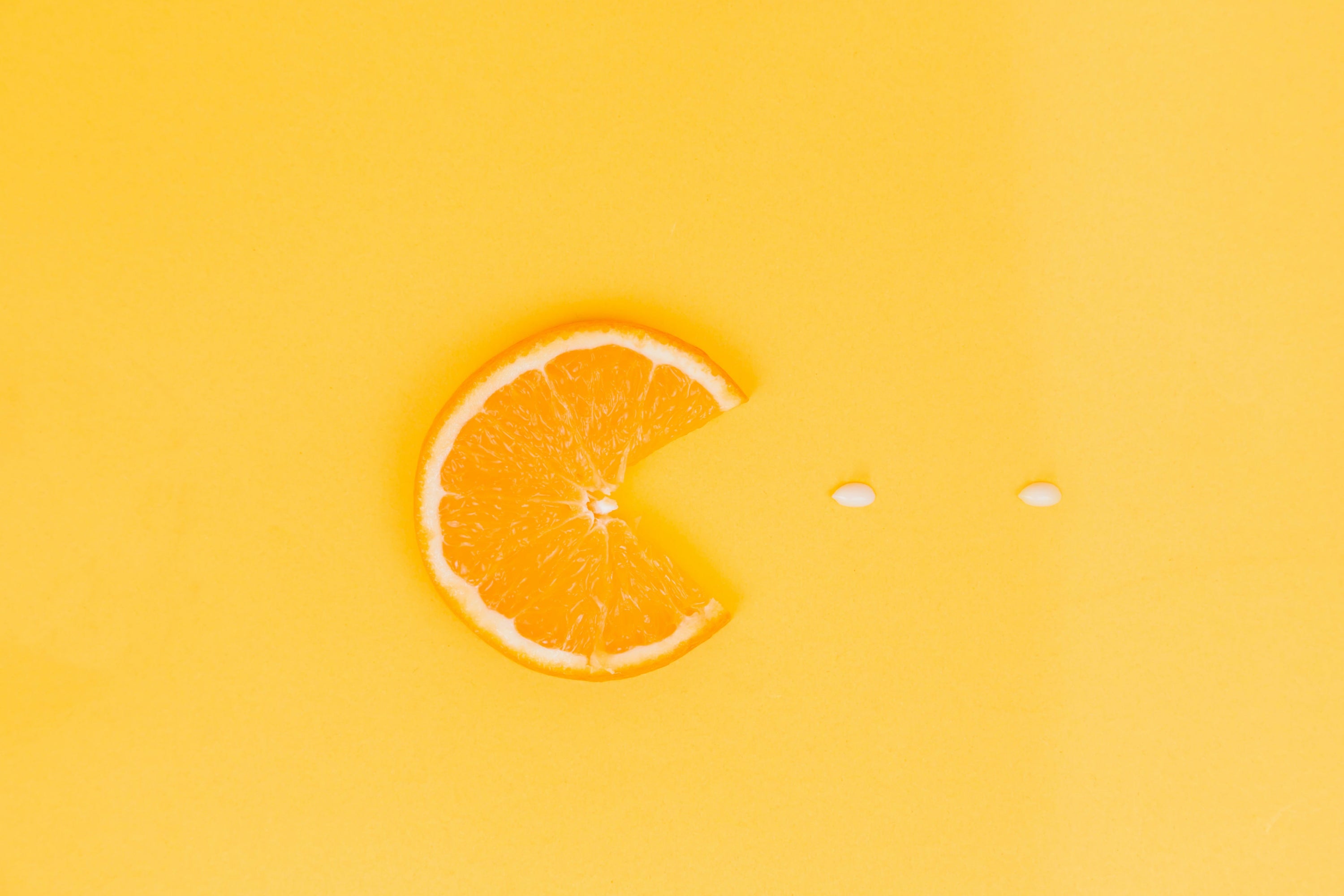 Orange slice with a bite taken out of it on a bright yellow background